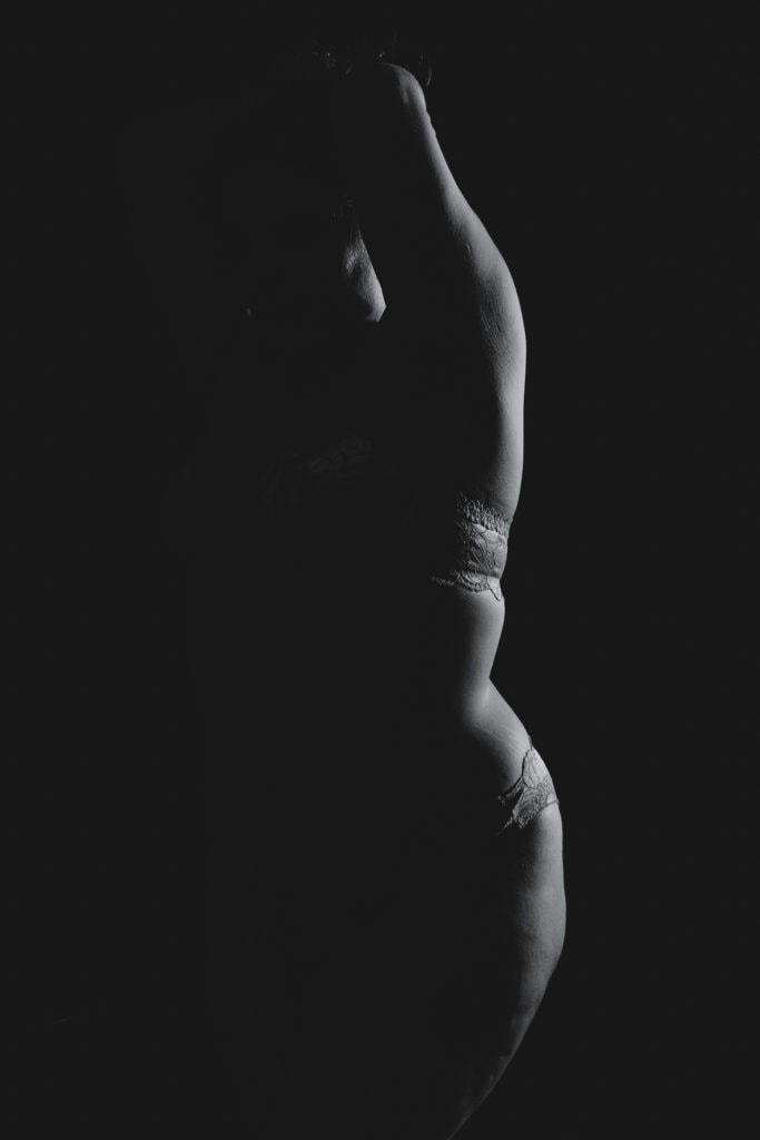 Bodyscape black and white silhouette of a curvy woman's body with her lace bra and panties. Featured in the blog post "Boudoir Inspo: Nudescape or Bodyscape Photography" nudescape, beautiful boudoir, boudoir style, imagery style, Colorado boudoir photographer, Body positive boudoir, Body Image, inspiration, style, black and white imagery, composition. Imagery by Embodied Art Boudoir.