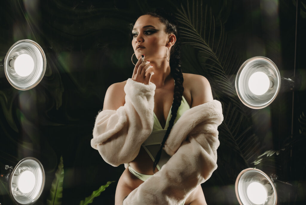 Elegant boudoir portrait of a woman in Denver with dramatic lighting and lush greenery backdrop.