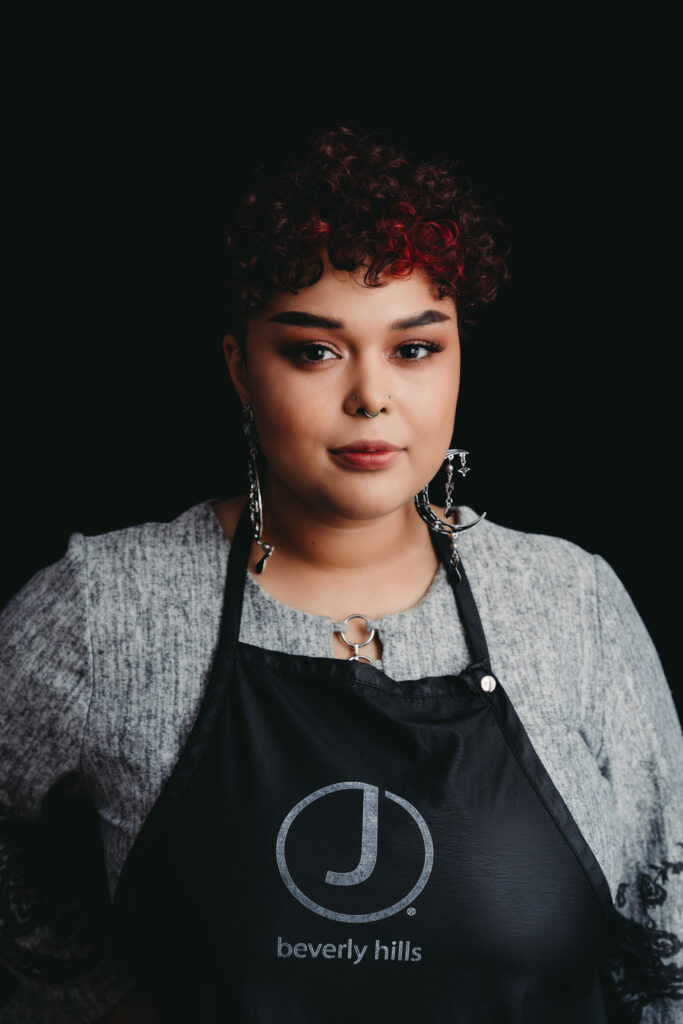 Woman facing and smiling to the camera wearing a black apron. Photo by Embodied Art Boudoir. outfit, outfit inspiration, look good, dress well, lingerie, casual, business casual, business formal, categories, clients, look good and feel good, stylish, personal style
