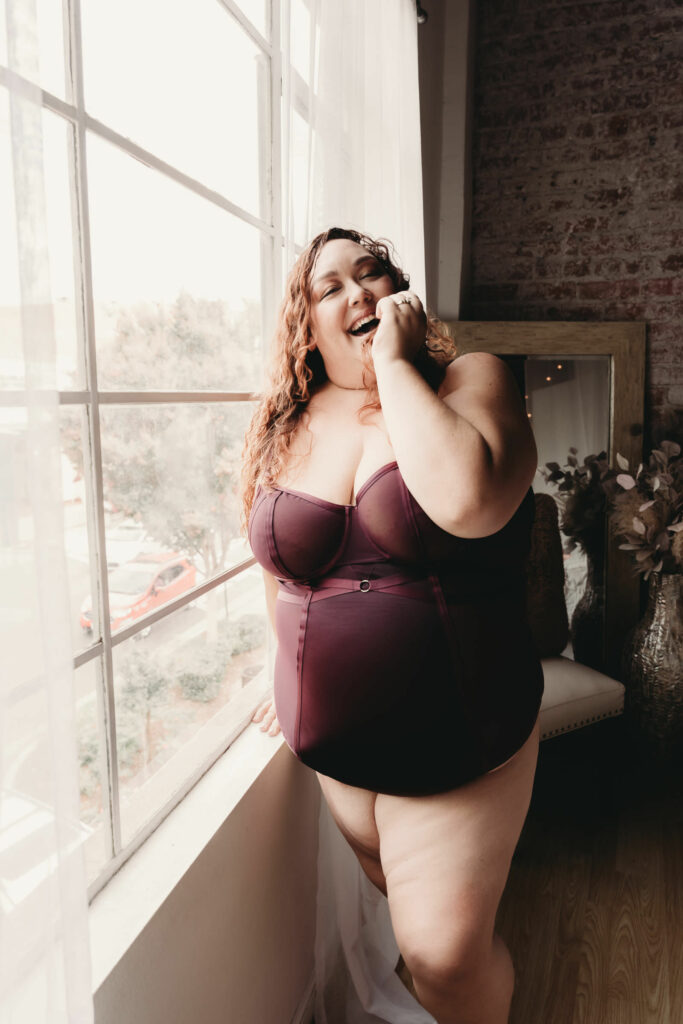 Woman standinging next to window wearing a dark purple body suit. Photo by Embodied Art Boudoir. Mindfulness, mindful practices, relax, relaxation, be present, destress, meditation, energize, female empowerment, expand your mind, self love, self care, colorado boudoir, denver boudoir, boulder boudoir, colorado springs boudoir