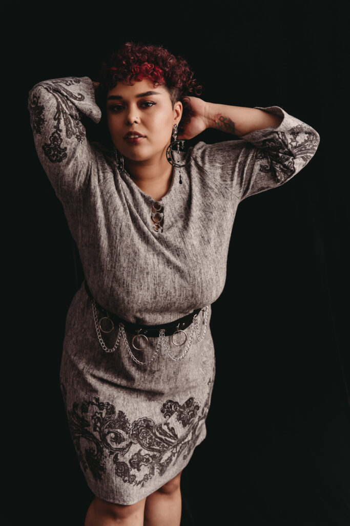 Woman standing hold her hair wearing a grey dress and smiling at camera. Bodyscape of womans body. Photo by Embodied Art Boudoir. Body positivity, body neutrality, female photographer, self acceptance, body journey, gratitude, self-love, self-growth, boudoir photoshoot, colorado boudoir, denver boudoir, boulder boudoir, colorado springs boudoir, boudoir ideas, boudoir poses, boudoir inspiration, photography inspiration