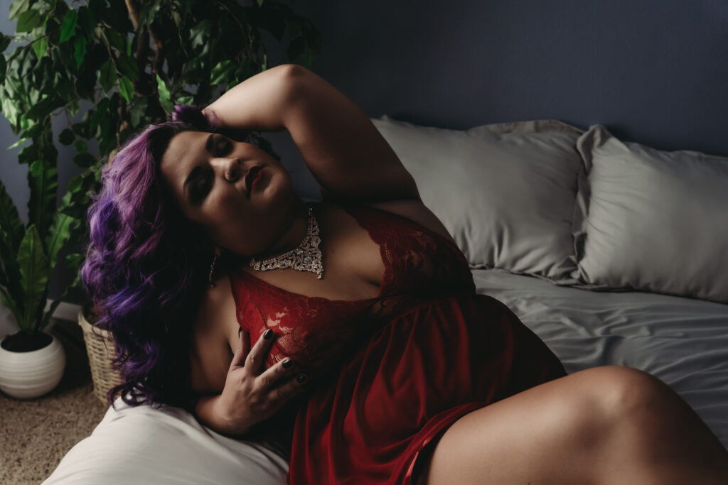Woman lying on bed wearing a bright orange baby doll and a diamond necklace with purple hair. Bodyscape of womans body. Photo by Embodied Art Boudoir. Body positivity, body neutrality, female photographer, self acceptance, body journey, gratitude, self-love, self-growth, boudoir photoshoot, colorado boudoir, denver boudoir, boulder boudoir, colorado springs boudoir, boudoir ideas, boudoir poses, boudoir inspiration, photography inspiration