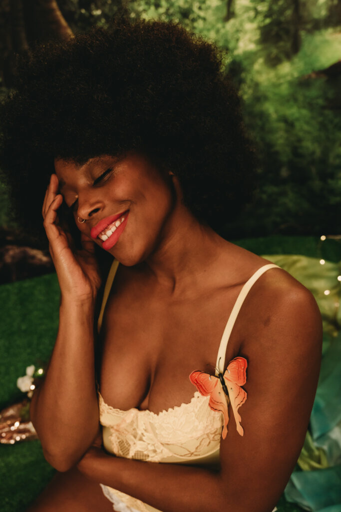 Woman wearing a white body suit with a pink butterfly on right side of shoulder, smiling. Photo by Embodied Art Boudoir. Personal growth, expanding your mind, growth, productivity, goal-getter, self-discovery, finding yourself, goal set, be yourself, challenge yourself, try new things, make changes, embrace change, expand your mind, be happy, evolution, get out of the comfort zone, colorado boudoir, denver boudoir, boulder boudoir, colorado springs boudoir, boudoir ideas