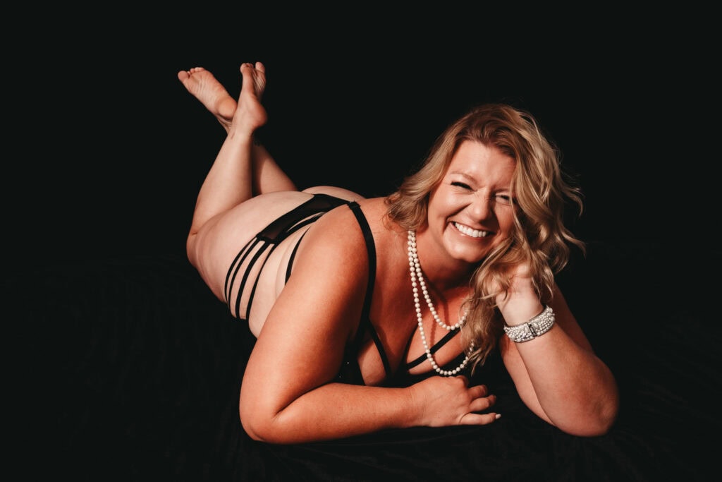 Blonde woman smiling at camera wearing a matching black bra and panties. Photo by Embodied Art Boudoir. Body positivity, body neutrality, female photographer, self acceptance, body journey, gratitude, self-love, self-growth, boudoir photoshoot, colorado boudoir, denver boudoir, boulder boudoir, colorado springs boudoir, boudoir ideas, boudoir poses, boudoir inspiration, photography inspiration