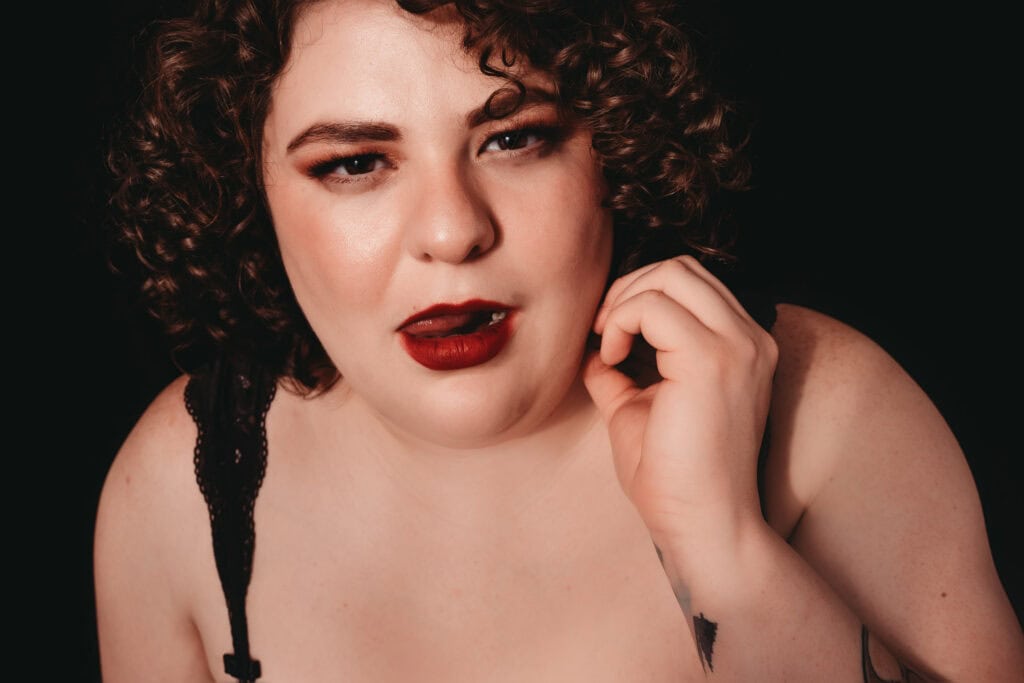 Curly headed woman with red lipstick smiling at camera, Photo by Embodied Art Boudoir. Holistic living, diet, lifestyle, intuitive eating, eat well, mindfulness, tips and tricks, healthy living, listen to your body, colorado boudoir, denver boudoir, boulder boudoir, colorado springs boudoir.